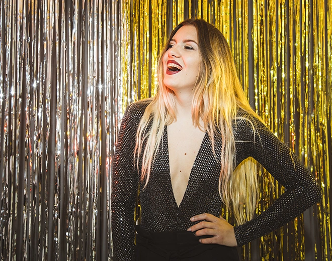 Confident woman smiling in glamorous outfit after cosmetic surgery transformation