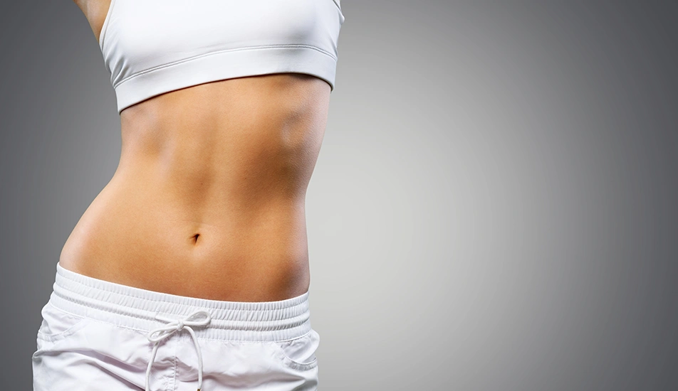 Close-up of slim female waist and flat stomach in white sportswear after Vaser liposuction