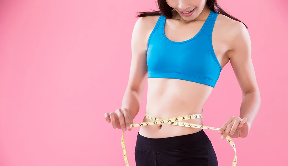 Woman measuring slim waist with tape after liposuction and body contouring
