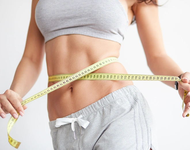 Close-up of woman measuring waist with tape measure after vaser lipo